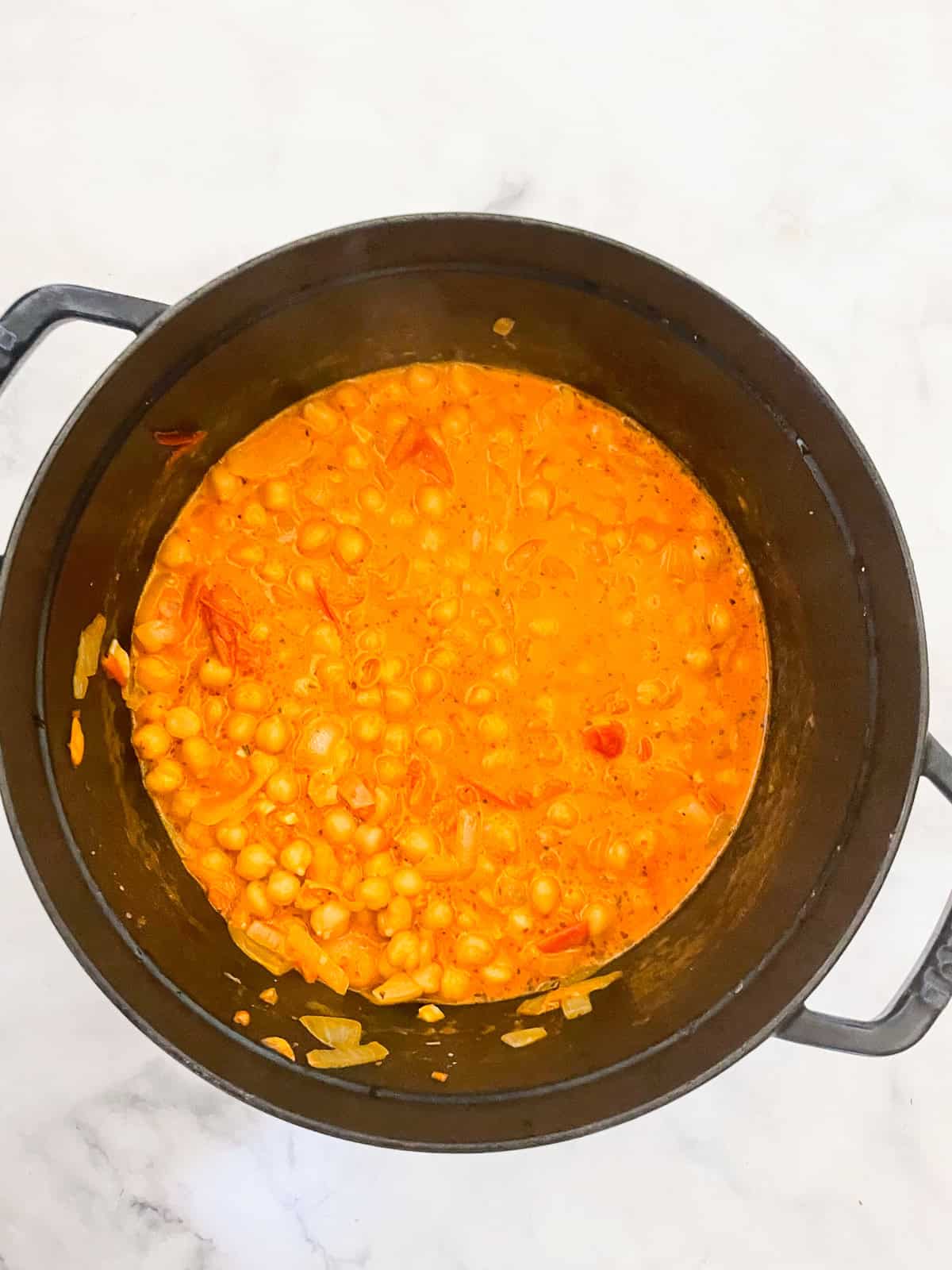 Marry me chickpeas is a vegetarian twist on a popular dish, featuring tender chickpeas and spinach in a tomato broth plus a splash of cream. Broth and cream are stirred in.