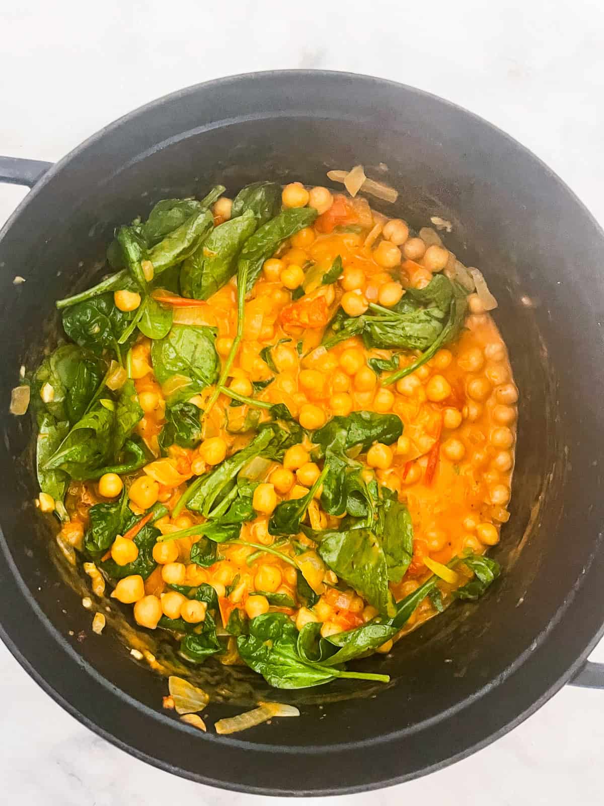 Marry me chickpeas is a vegetarian twist on a popular dish, featuring tender chickpeas and spinach in a tomato broth plus a splash of cream. Spinach cooks into the broth for marry me chickpeas.