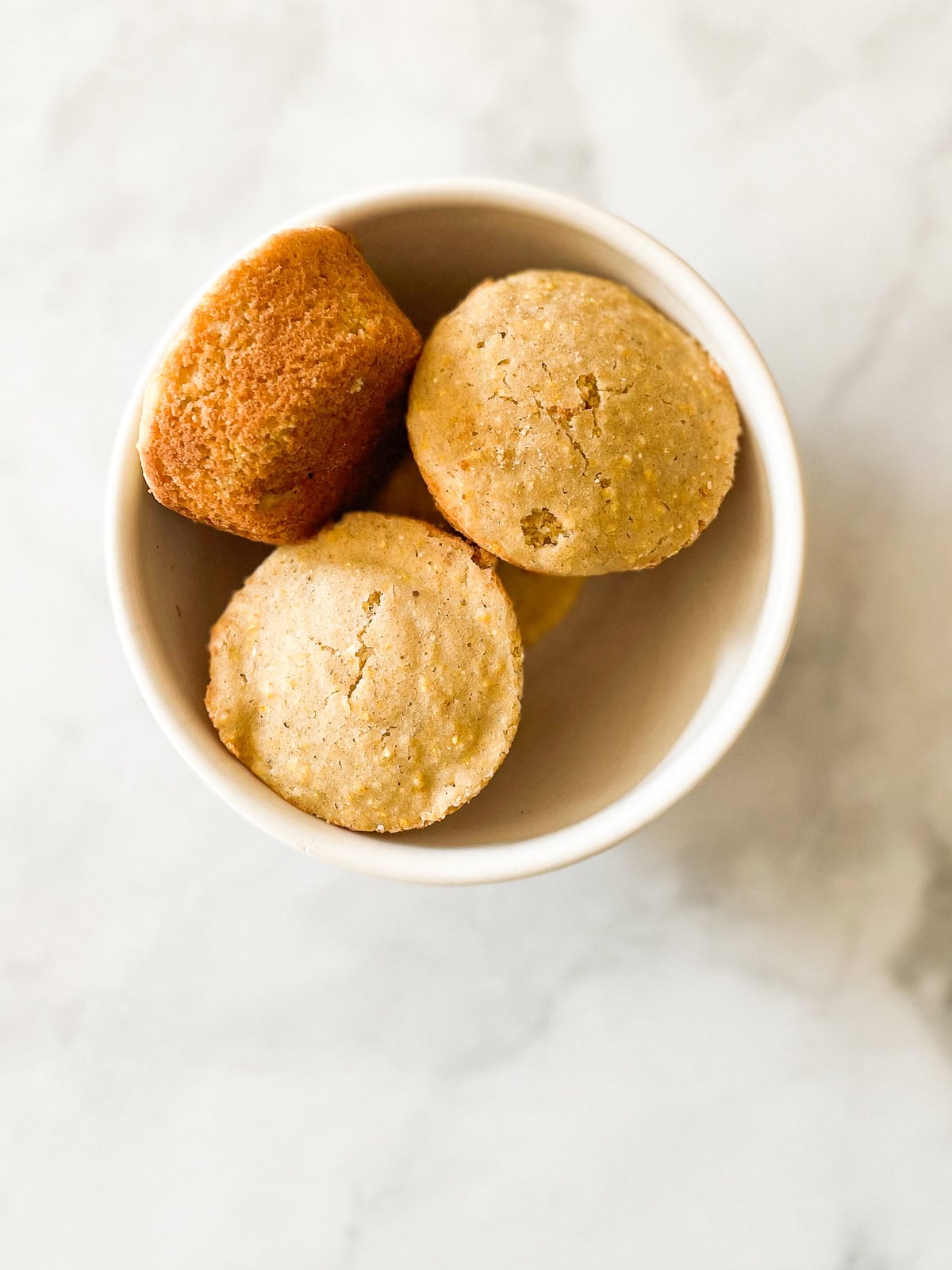 A white bowl of gluten free cornbread muffins.