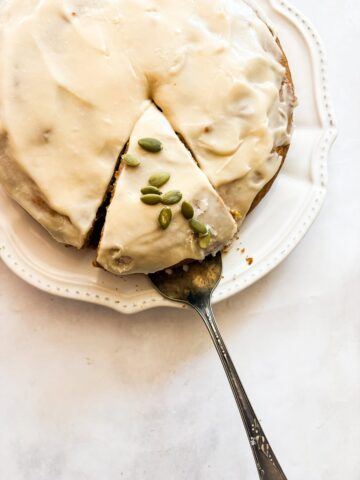 A cake server lifts out a slice of pumpkin olive oil cake.