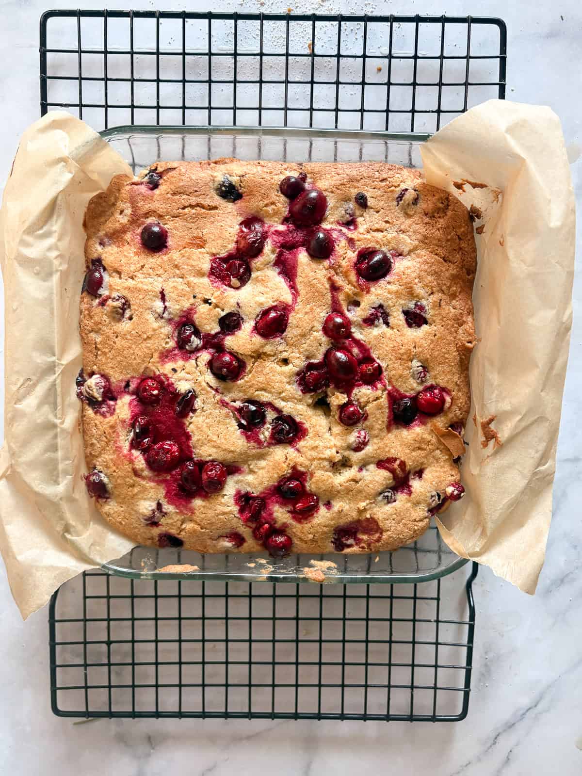 Studded with juicy berries, this sweet and soft cranberry cake is a lovely holiday bake. Great with brunch, or as dessert with ice cream. A cranberry cake cools in the pan.
