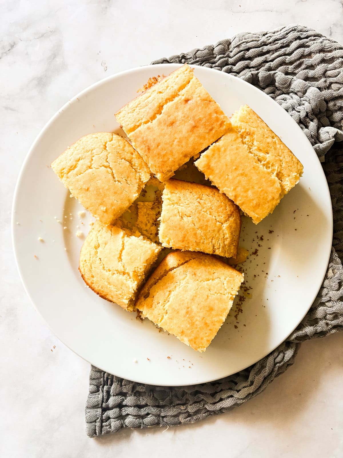 Squares of homemade cornbread on a white serving plate.