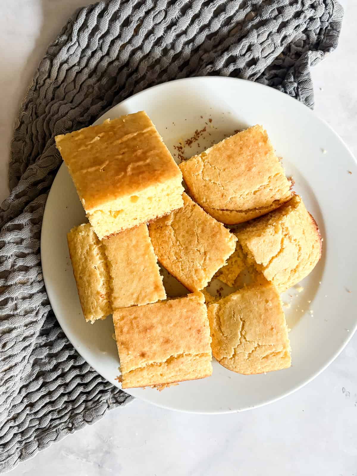 A delicious, lightly sweet homemade cornbread recipe that's made in 1 bowl. Perfect with your favorite soup, stew or chili. Squares of homemade cornbread on a p late.