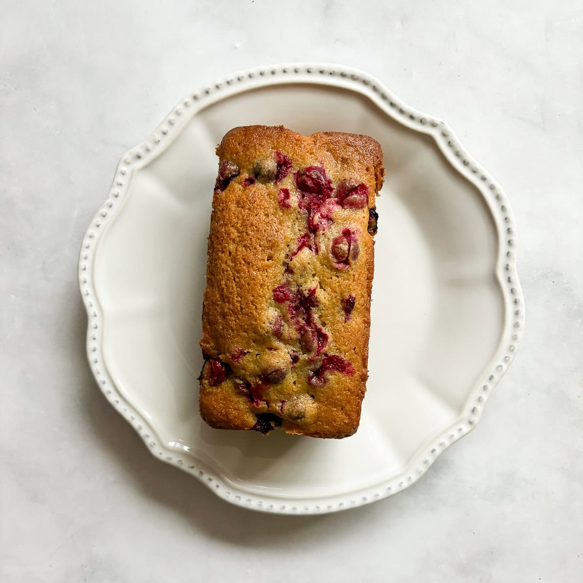 A loaf of lemon cranberry bread on a plate.