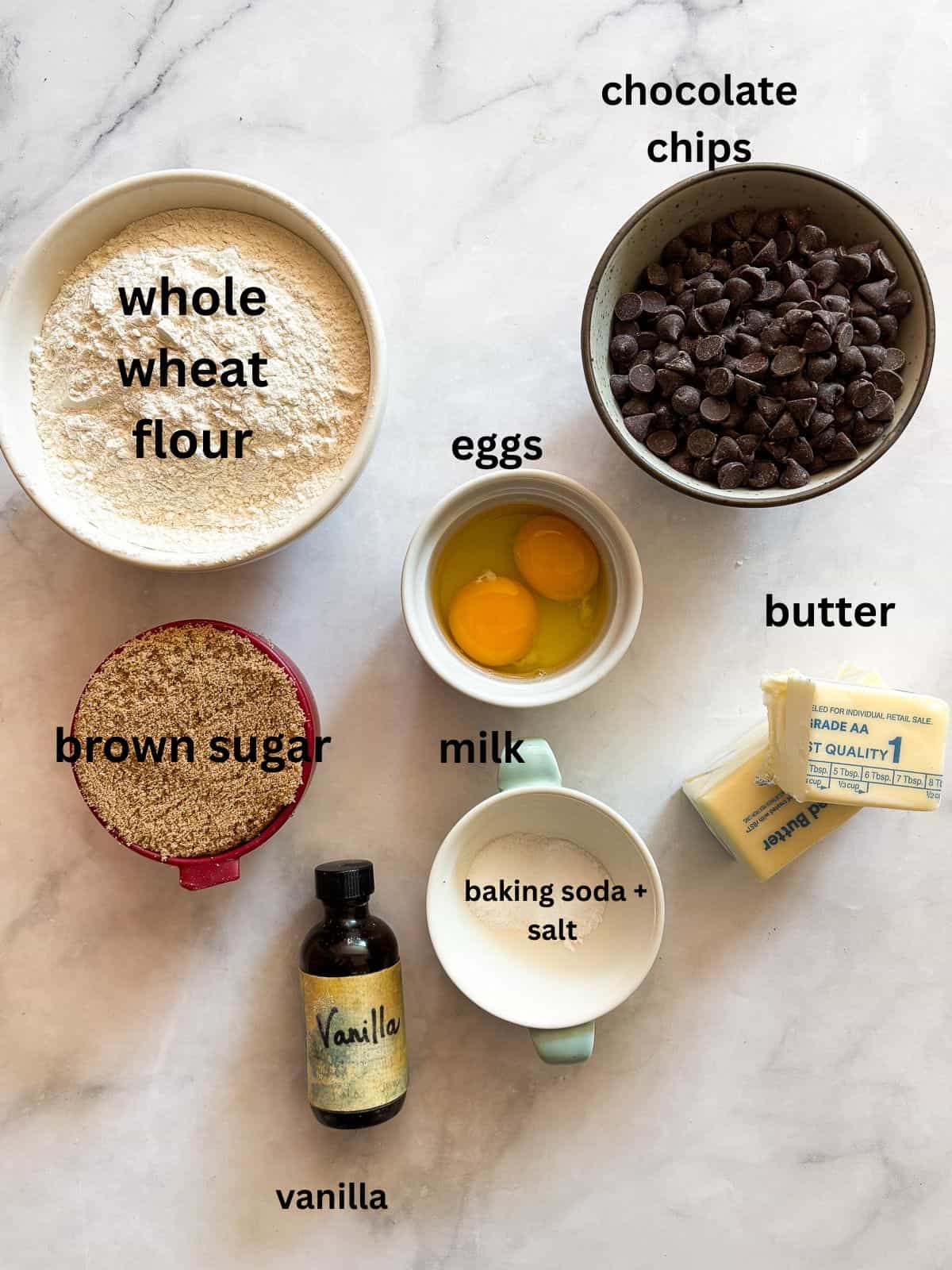 This buttery chocolate chip cookie cake is made with whole wheat flour and brown sugar for a touch of caramel sweetness. Ingredients for chocolate chip cookie cake are portioned and text-labeled.