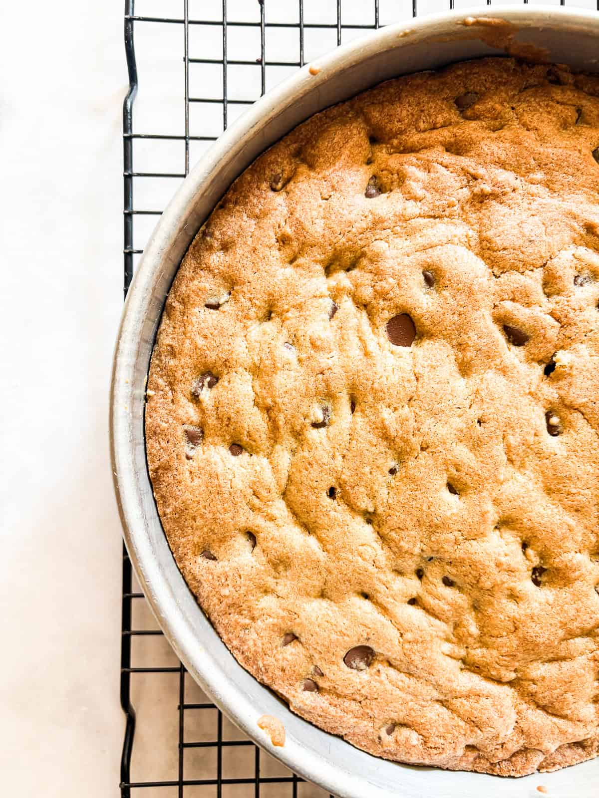 This buttery chocolate chip cookie cake is made with whole wheat flour and brown sugar for a touch of caramel sweetness. A golden brown baked chocolate chip cookie cake.