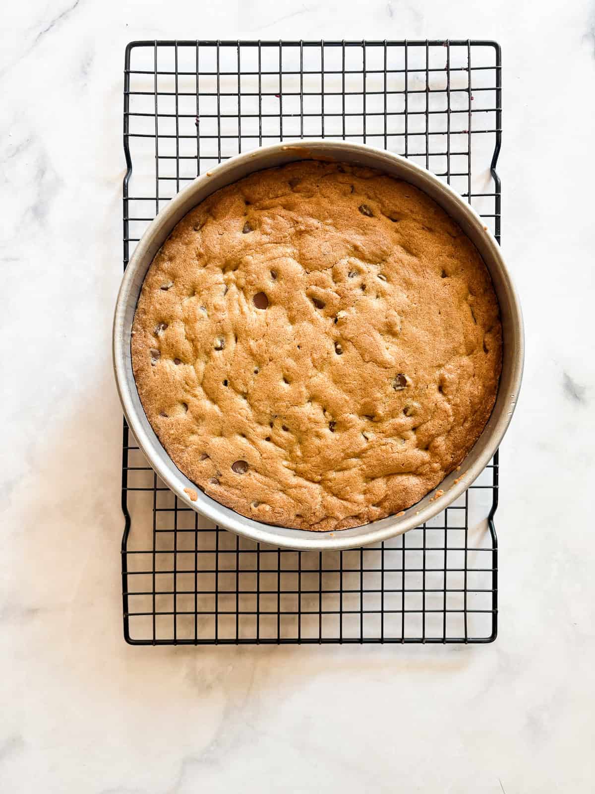 This buttery chocolate chip cookie cake is made with whole wheat flour and brown sugar for a touch of caramel sweetness. A chocolate chip cookie cake cools in the pan.