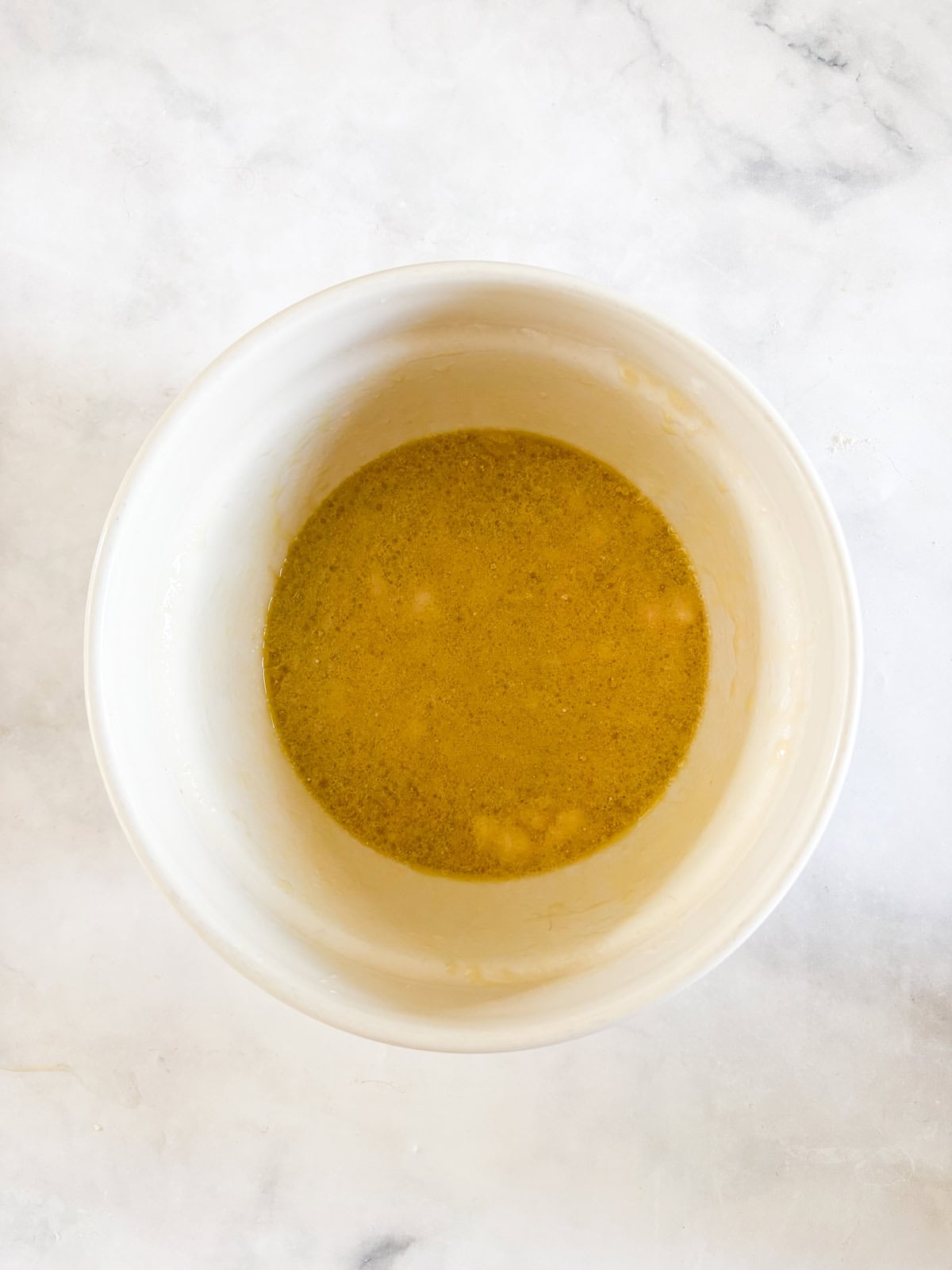 These perfect bite-sized mini banana muffins are made with whole-grain flour, maple syrup, and heart-healthy olive oil. Mini banana muffins battet in a bowl.