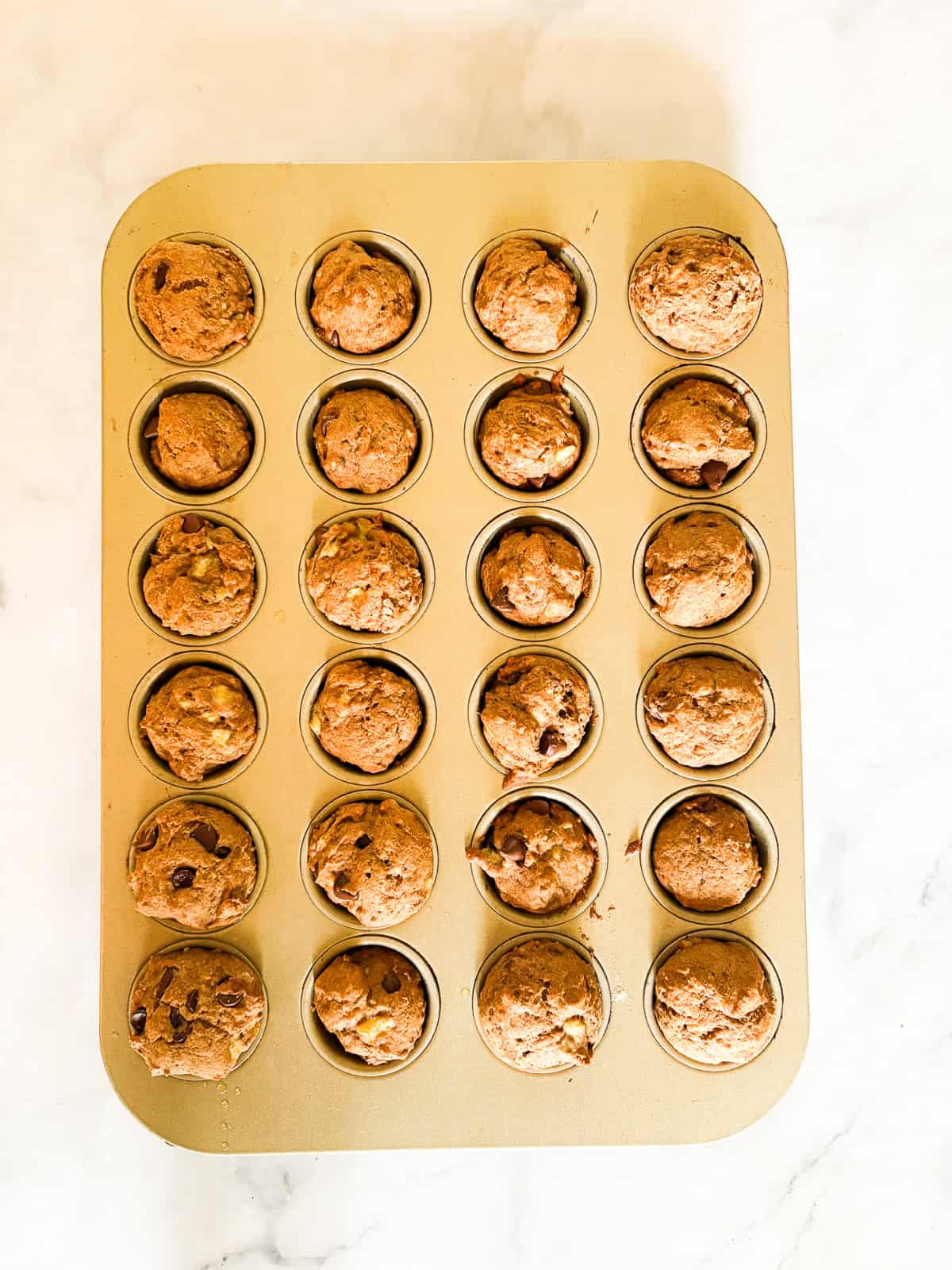 These perfect bite-sized mini banana muffins are made with whole-grain flour, maple syrup, and heart-healthy olive oil. Mini banana muffins after being baked in the muffin tin.