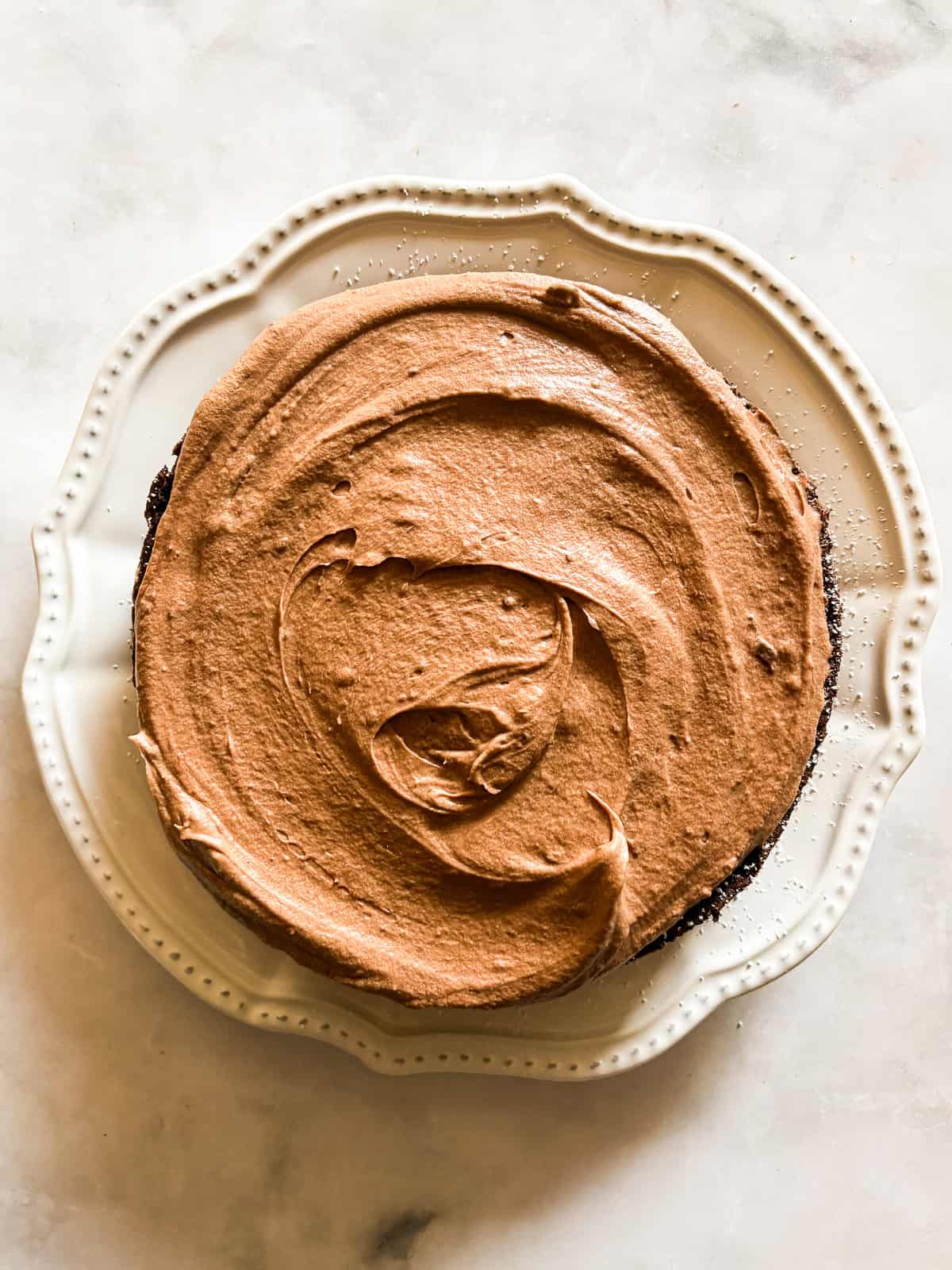 A beyond easy one-layer vegan chocolate cake recipe made in one bowl with pantry staples. Top with your fav frosting. A vegan chocolate cake topped with frosting.