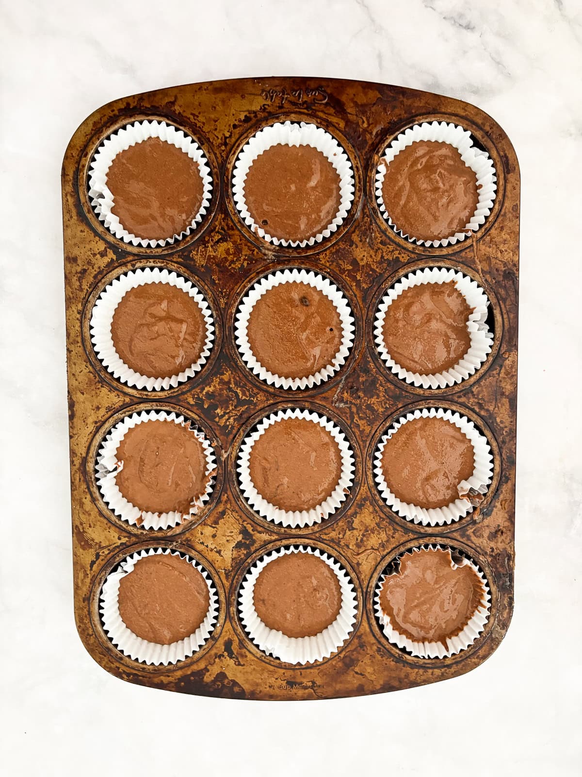 Tender, chocolatey vegan chocolate cupcakes frosted with a sumptuous vegan chocolate buttercream are out-of-this-world good! Batter is portioned into a muffin tin for vegan chocolate cupcakes.