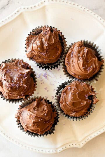 Four vegan chocolate cupcakes on a plate.